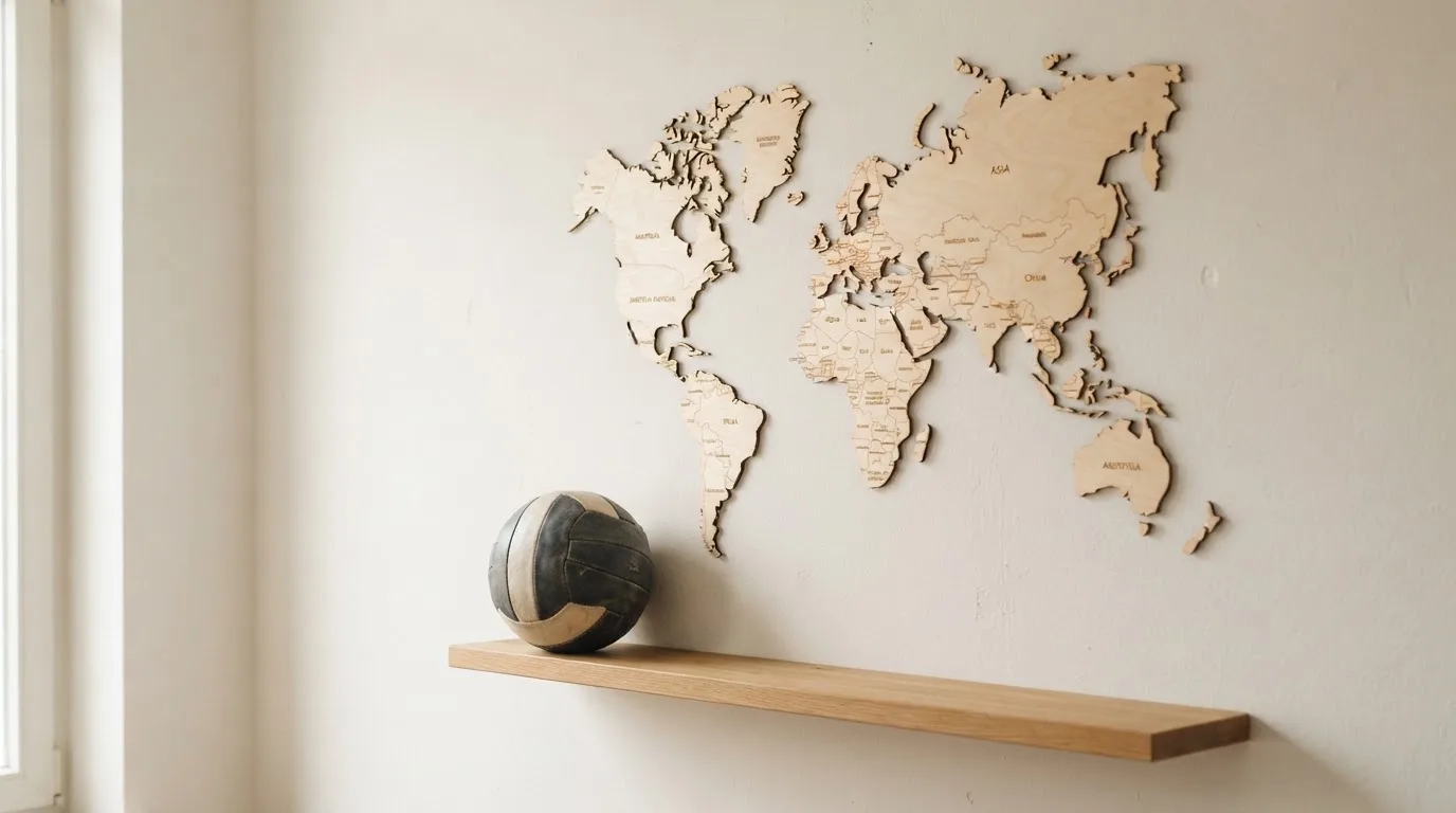 Eine Weltkarte aus Holz hängt an einer Wand, davor liegt ein Fußball auf einem Regal, ohne erkennbare Beschriftung.