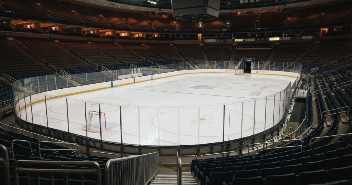 Eine Eishockeyhalle von der Tribüne aus gesehen, spiegelglatte Eisfläche, Banden ohne Schriftzüge, helles Flutlicht.
